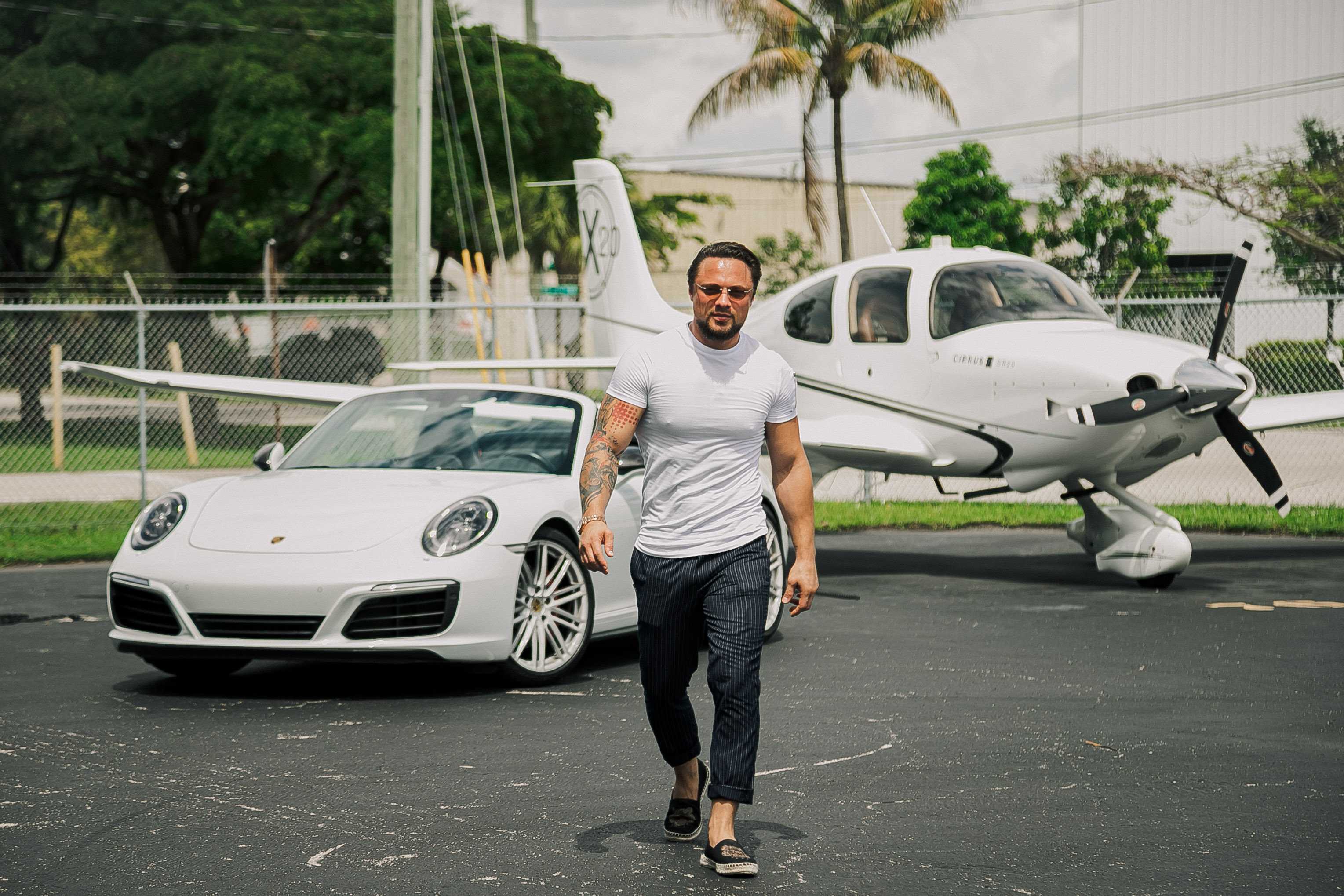 Pugachev archive photograph beside a white Porsche and an aircraft