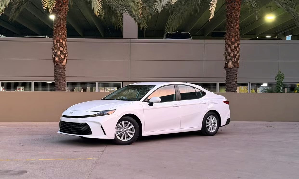 Front three-quarter view of the white Toyota Camry Hybrid LE