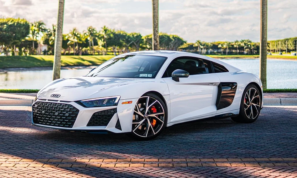 White Audi R8 V10 Performance, front three-quarter view beside palm trees