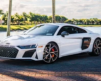 White Audi R8 V10 Performance, front three-quarter view beside palm trees