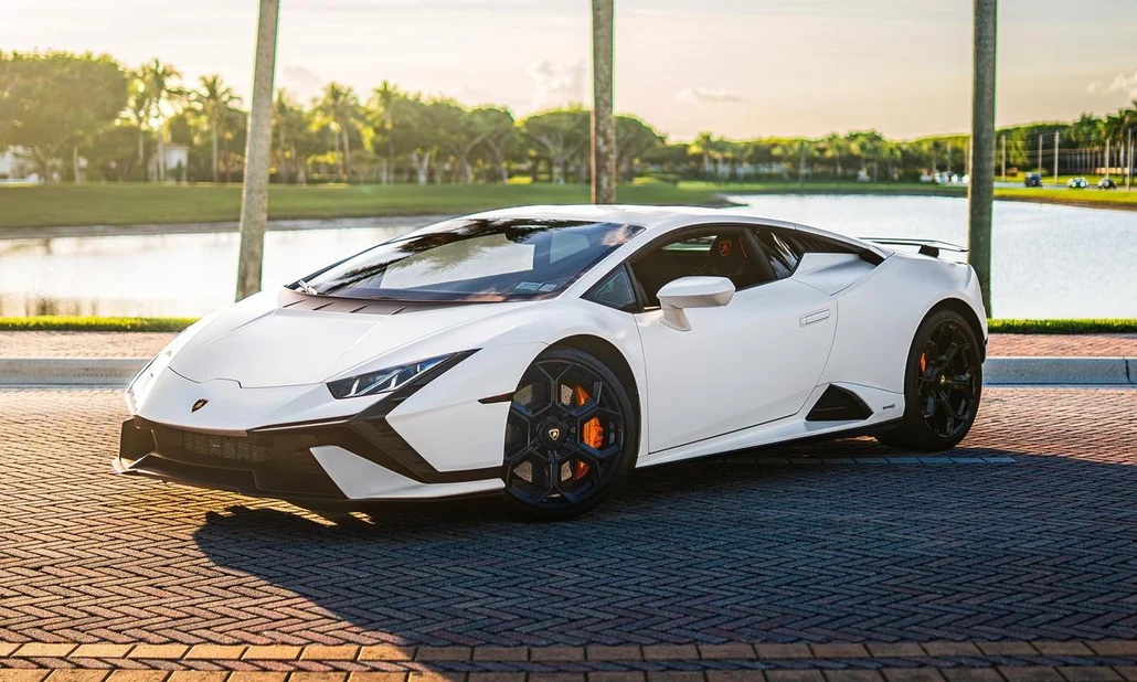 White Lamborghini Huracan Tecnica Rental in Miami, front three-quarter view beside palms