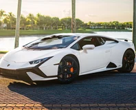 White Lamborghini Huracan Tecnica Rental in Miami, front three-quarter view beside palms